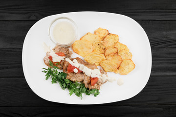 Grilled chicken breast with potatoes and sauce.