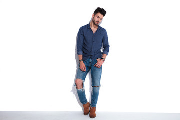 Naklejka premium sexy man in navy shirt leaning against a white wall