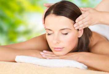 Obraz na płótnie Canvas wellness, spa and beauty concept - close up of beautiful woman having head massage over green natural background