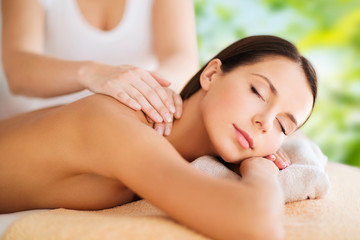Obraz na płótnie Canvas wellness, spa and beauty concept - close up of beautiful woman having massage over green natural background
