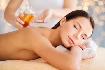wellness, spa and beauty concept - close up of beautiful woman having massage over holidays lights background