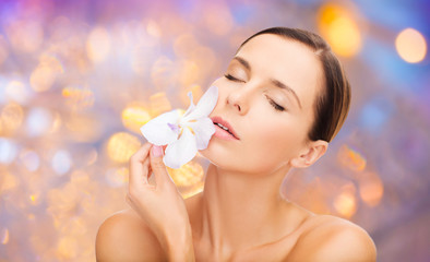 wellness and beauty concept - beautiful bare woman with orchid flower over holidays lights background