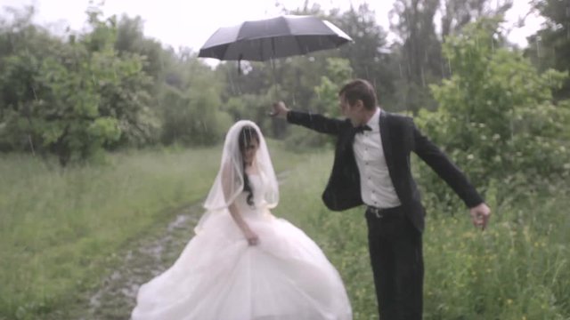 Happy and happy newlyweds with umbrella in the rain. wedding in the rain.