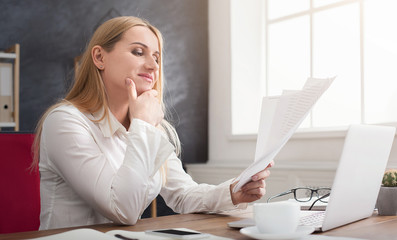 Concentrated businesswoman checking documents at office