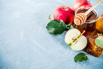 Jewish holiday Rosh Hashanah or apple feast day concept, with red apples, apple leaves and honey in jar, light blue background copy space above