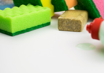 Multicolored foam rubber sponges, soap on a light background.