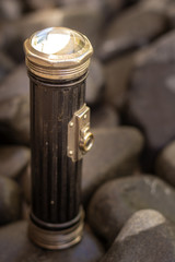 Obraz na płótnie Canvas Close up shot of a antique 1920`s flashlight in pebbles background, vintage concept.