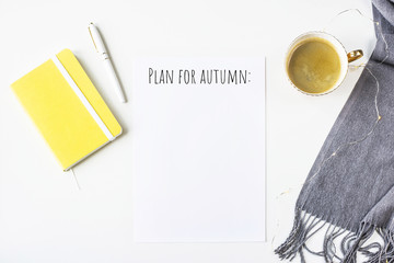 Autumn notes on a white table next to a scarf, yellow notepad with a pen and a cup of coffee. Plan...