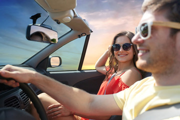 leisure, road trip, travel, summer holidays and people concept - happy couple driving in convertible car over sky background