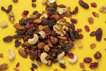 Mix of dried fruits and nuts on a yellow background
