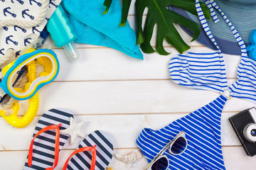 Beachwear and accessories on a white wooden background