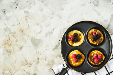 Pan with pancakes and raspberries and blackberries on a gray table. Top view, flat lay, copy space