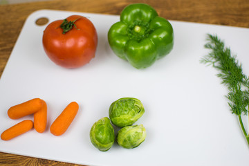 Fresh vegetables on a white cutting board.