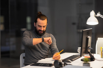 deadline, technology and people concept - creative man with smartwatch using voice command recorder and working late at night office