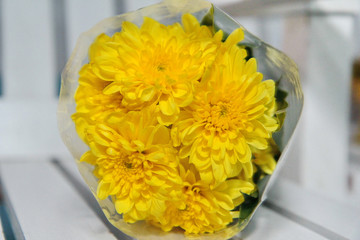 Colorful yellow flowers bouquet is a combination rests on white wood.