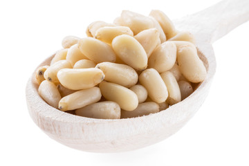 Pine nuts in the wooden scoop. White background.