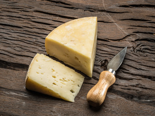 Pieces of homemade cheese on the wooden background.
