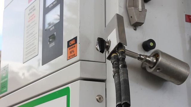 A man puts the natural gas (cng) filling hose away.