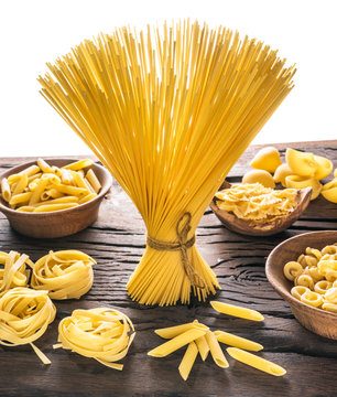 Different pasta types on wooden table. White background.