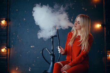 girl smokes  hookah / beautiful glamorous girl in red dress smokes a hookah, the sexy model in a night club smokes © kichigin19