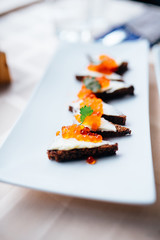 red caviar smeared with black bread on a platter