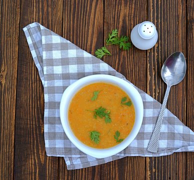 Popular Israeli orange soup cream with pumpkin, carrots, sweet potato and red lentils on a wooden background
