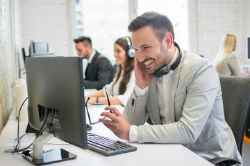 Happy business man with eyeglasses in hand looking at computer screen in office