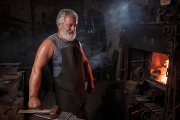 Portrait of a blacksmith artisan in an apron with an anvil in a blacksmith