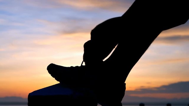 Running shoes - Man is tying shoe laces. male sport fitness runner getting ready for jogging outdoors the time during sunrise on dam road exercise. slow motion