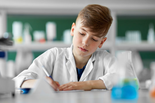 education, science and children concept - boy with notebook studying biology at school