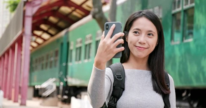 Woman taking photo by mobile phone on train station