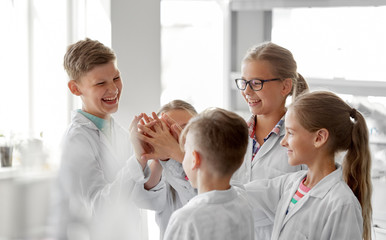 education, science and children concept - happy kids making high five at school laboratory