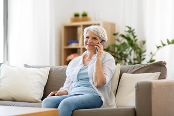 technology, communication and people concept - happy senior woman calling on smartphone at home