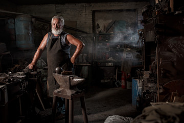 Fototapeta na wymiar Portrait of a blacksmith artisan with a hammer in a blacksmith