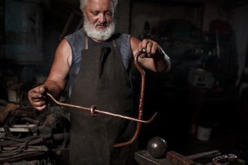 The portrait of blacksmith preparing to work metal on the anvil
