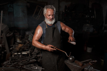 The portrait of blacksmith preparing to work metal on the anvil