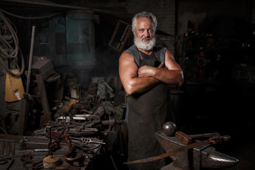 Fototapeta na wymiar The portrait of blacksmith preparing to work metal on the anvil