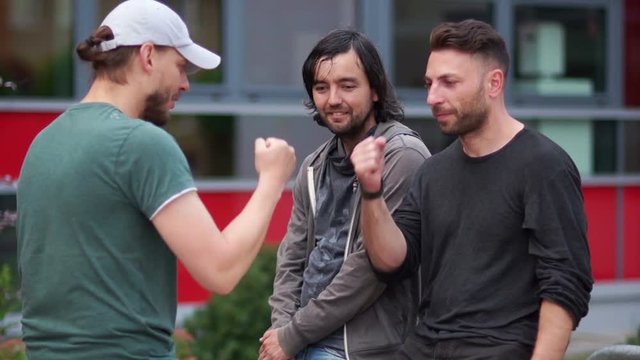 Three handsome young men with beards smiling and talking. Good-looking guys plaing rock-paper-scissors. They laugh and gesticulate