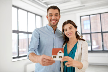 Obraz premium mortgage, people and real estate concept - happy couple with house model at empty room of new home