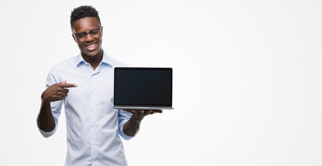 Young african american businessman using computer laptop very happy pointing with hand and finger
