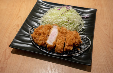 Fried pork tongkatsu with vegetable in black ceramic plate