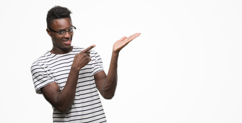 Young african american man wearing glasses and navy t-shirt amazed and smiling to the camera while...