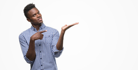 Young african american man wearing blue shirt amazed and smiling to the camera while presenting...