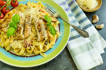 Traditional Italian tagliatelle pasta with cherry tomatoes and fried chicken on a large plate