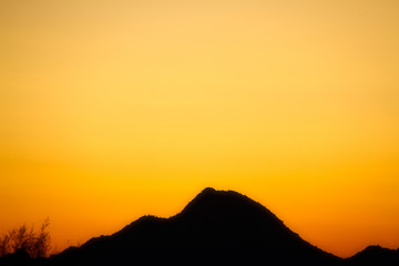 A silhouette of a desert mountain with the sky providing copy space.