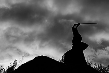 Silhouette black and white photo warrior with sword on the mountain