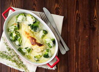 Chicken fillet baked with broccoli in bechamel sauce on wooden table. Healthy food, clean eating, top view, copy space