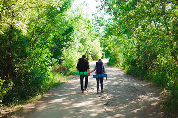 Young couple hikers in forest. sports man and woman with backpacks on road in nature