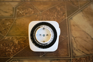 Electrical outlet with timer on brown background. Adjustment of the electrical outlet with a 24-hour timer program.