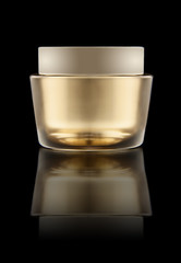 glass can with cream and gold lid isolated on black background